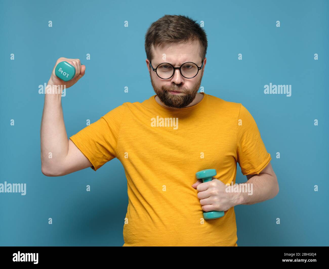 Un hombre extraño con gafas redondas con sobrepeso decidió ir a practicar  deportes, tomó pequeñas pesas en las manos y estaba listo para el  entrenamiento Fotografía de stock - Alamy