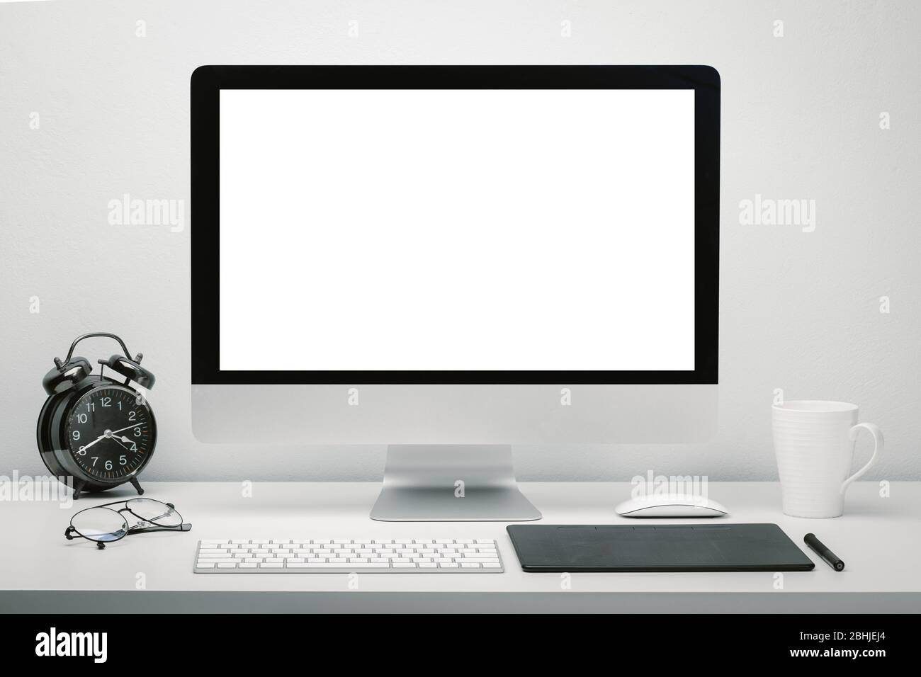 matar hormigón solamente Elegante espacio de trabajo con pantalla en blanco para ordenador, que se  puede poner en marcha en el escritorio con teclado, ratón, taza de café,  reloj, gafas y pen tablet Fotografía de