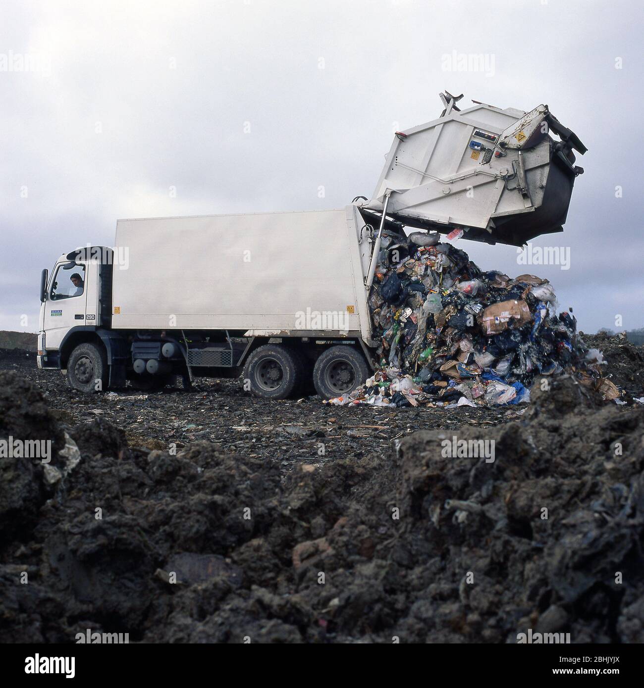 Descargue camiones de basura en un sitio de llenado de tierra. Foto de stock