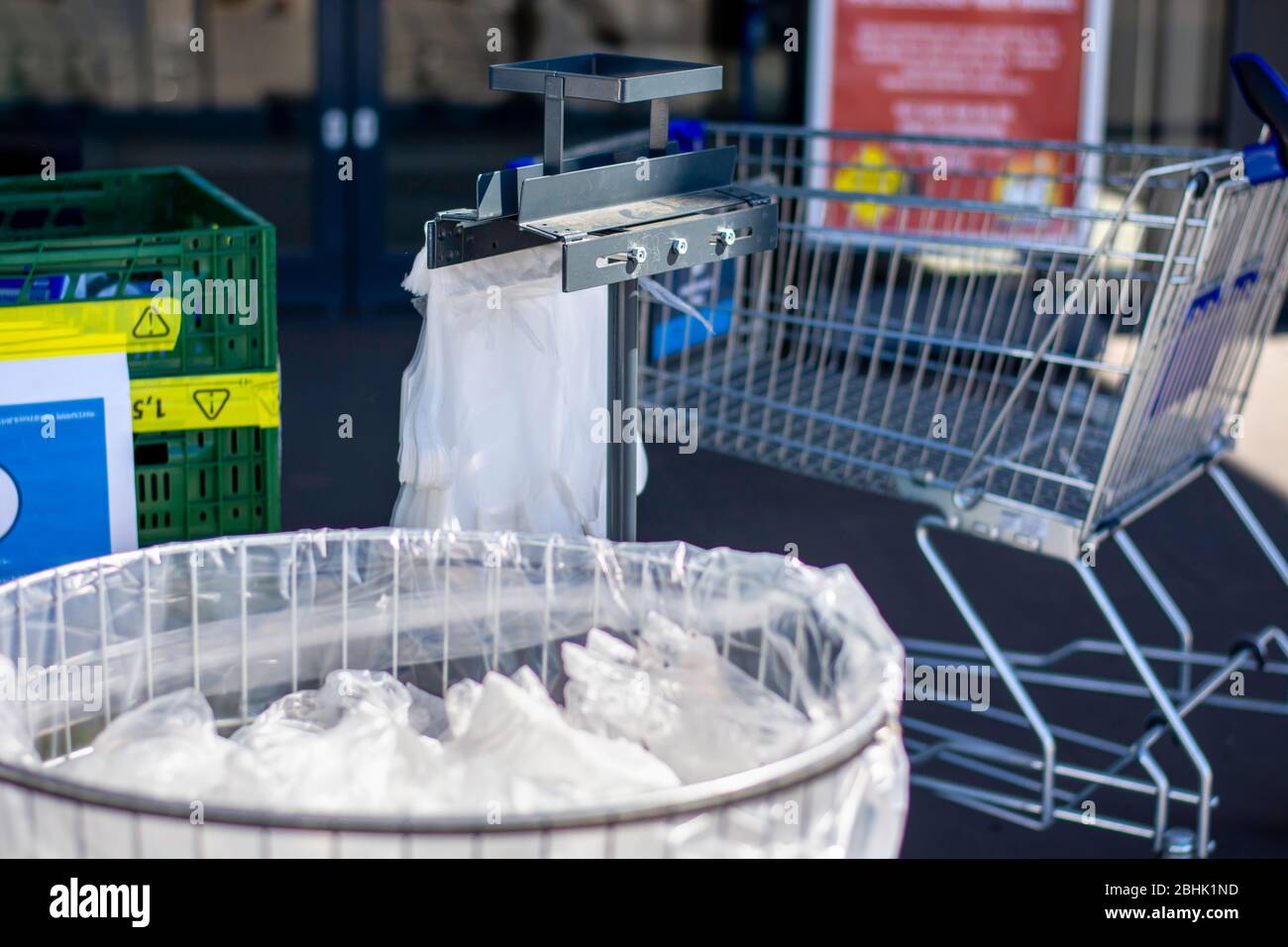 Papelera llena de toallitas desechables usadas y guantes de plástico en la entrada de un supermercado para proteger a los clientes contra la infección por coronavirus covid-19 Foto de stock