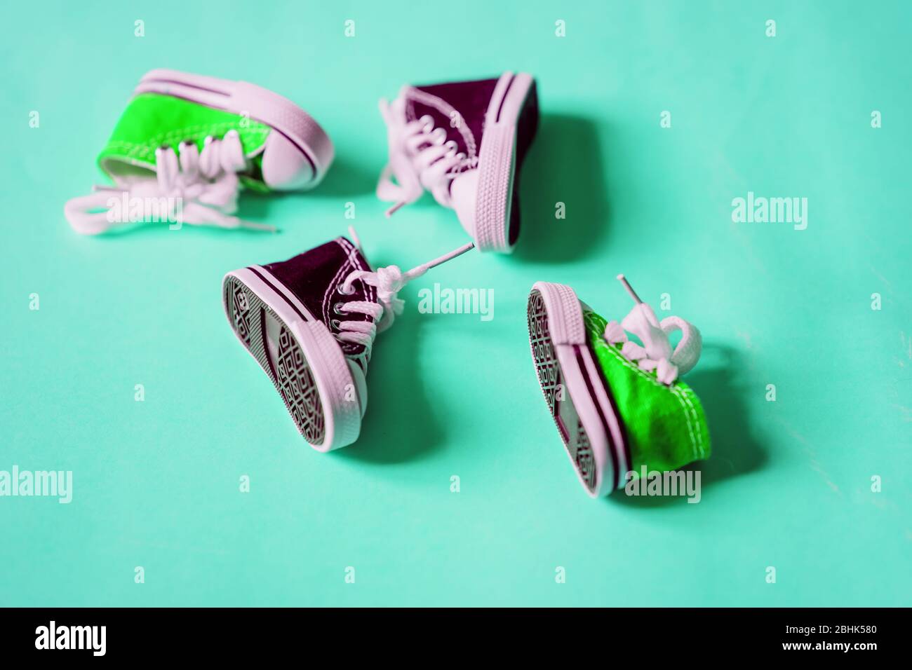 Elegantes y bonitas sneakers para bebés pequeñas, verdes y violetas, con  los brazos blancos aislados sobre fondo de color menta y espacio para  copias. Zapatos en miniatura. Vista superior, plana Fotografía de