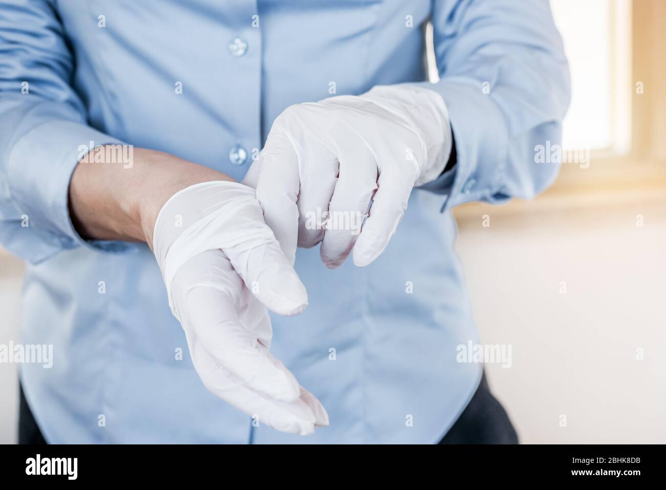 Mujer poniendo guantes desechables de látex como protección contra la propagación del coronavirus. Producto de protección individual. Pandemia de Covid-19. Foto de stock