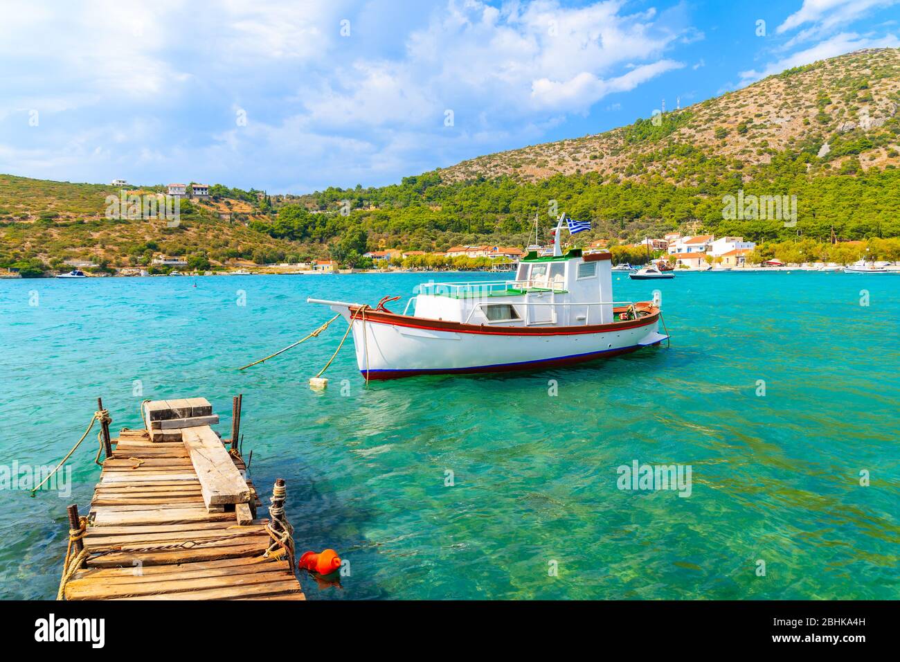Muelle de madera y colorido barco pesquero griego en el mar turquesa en la bahía de Posidonio, isla de Samos, Grecia Foto de stock