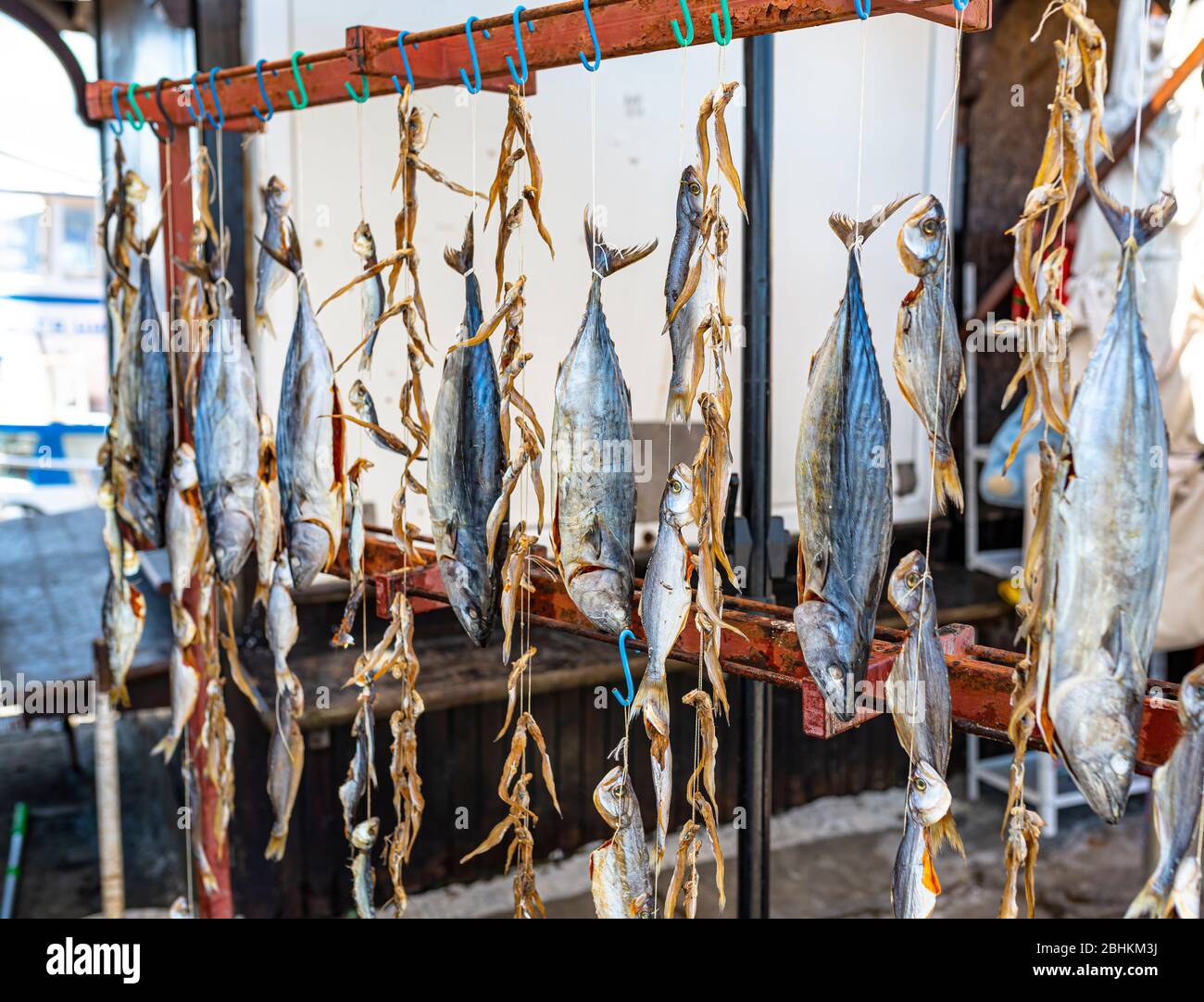 Pescado seco de mar colgado en ganchos en un mercado de pescado local. Foto de stock