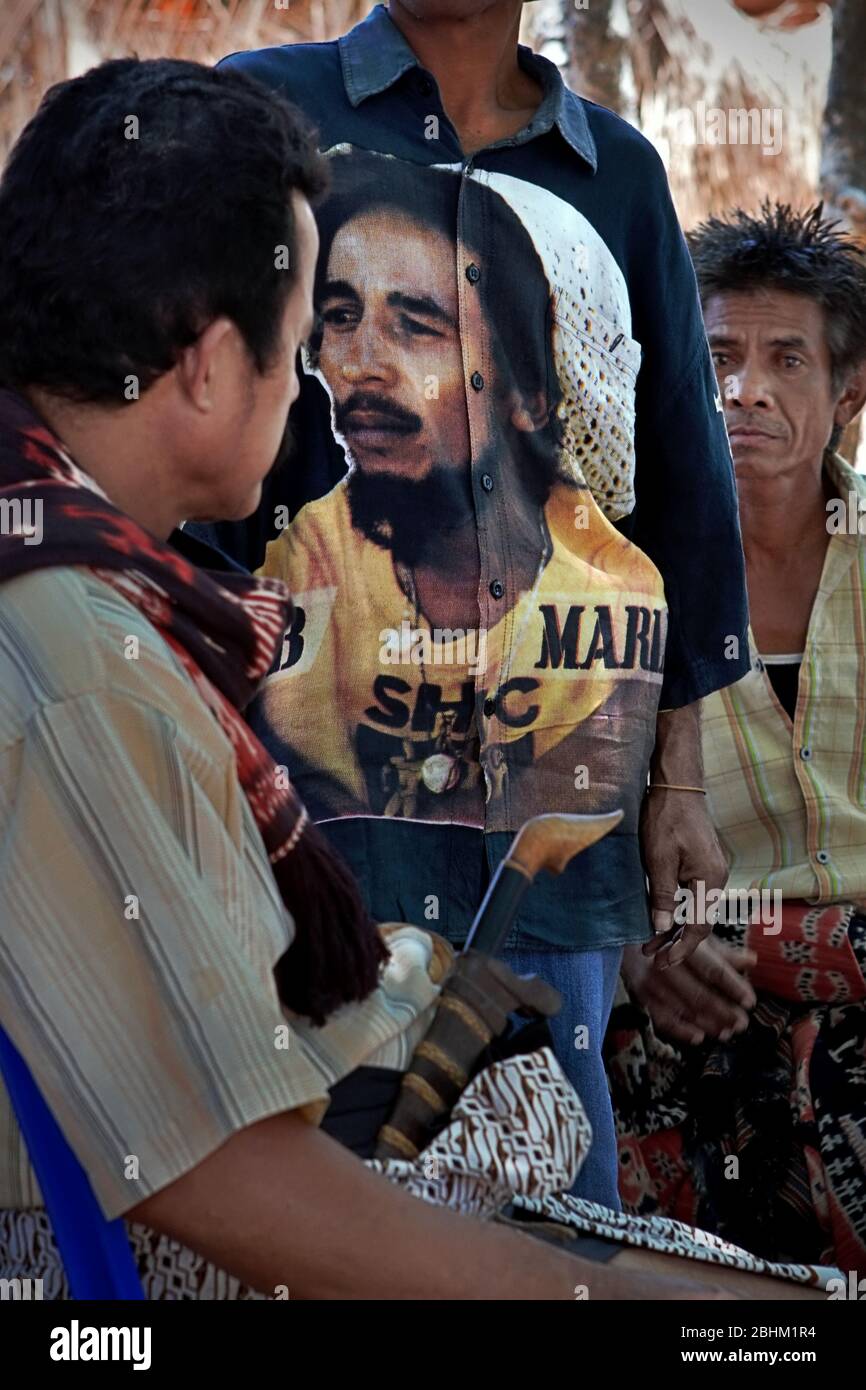 Hombre vestido con una camisa decorada con el retrato de Bob Marley durante una reunión comunitaria en la isla de Sumba, Indonesia. Foto de stock