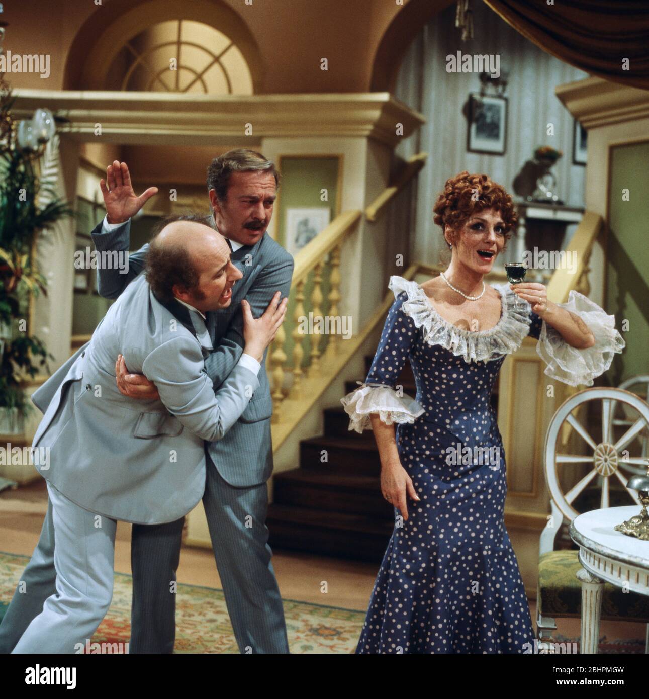 Siegfried Kernen hält Horst Naumann zurück während Gaby Gasser ein Gläschen trinkt in Herkulespillen, Regie: Michael Günther, 1980. Siegfried Kernen refrenando a Horst Naumann como Gaby Gasser está tomando una bebida en Herkulespillen, Director: Michael Günther, 1980. Foto de stock