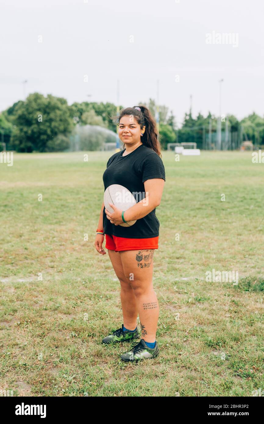 Una mujer de pie en un campo de entrenamiento con cortos y sosteniendo un de rugby de stock - Alamy