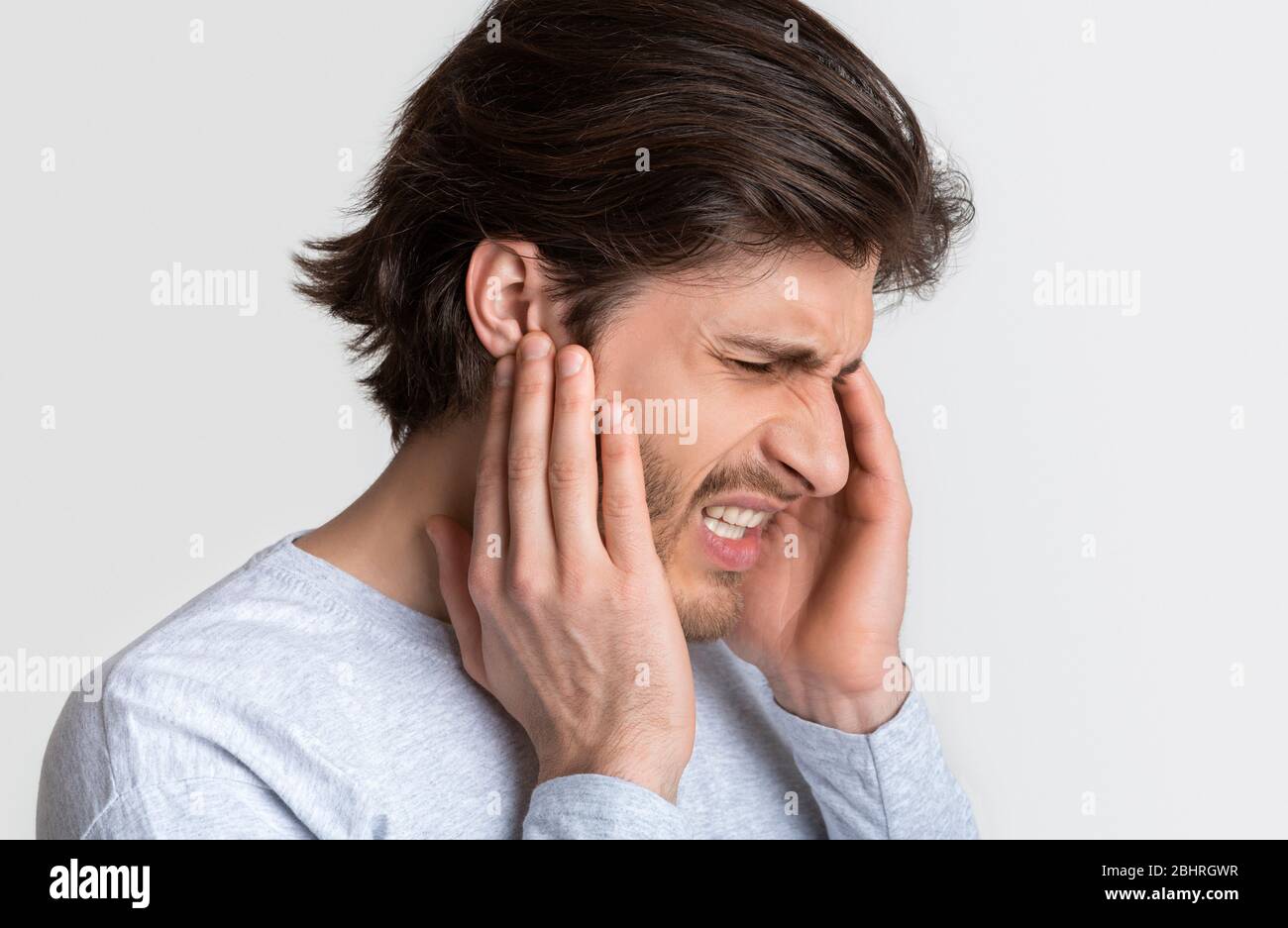 El hombre con dolor de oído está sosteniendo el punto dolorido Foto de stock