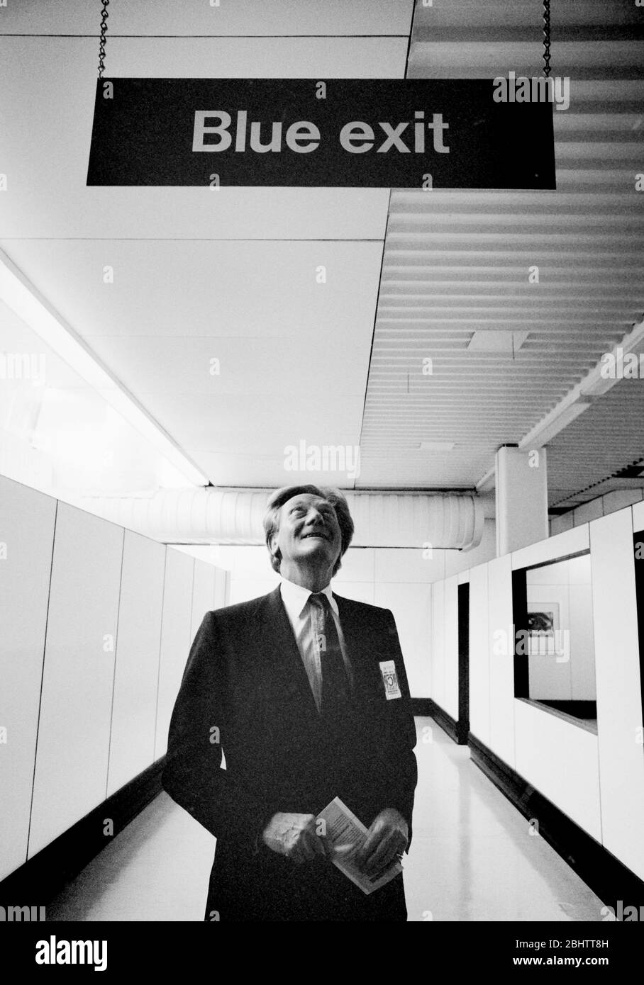Michael Heseltine debajo de una señal de salida en el aeropuerto de Heathrow a principios de los años 90. Foto de stock