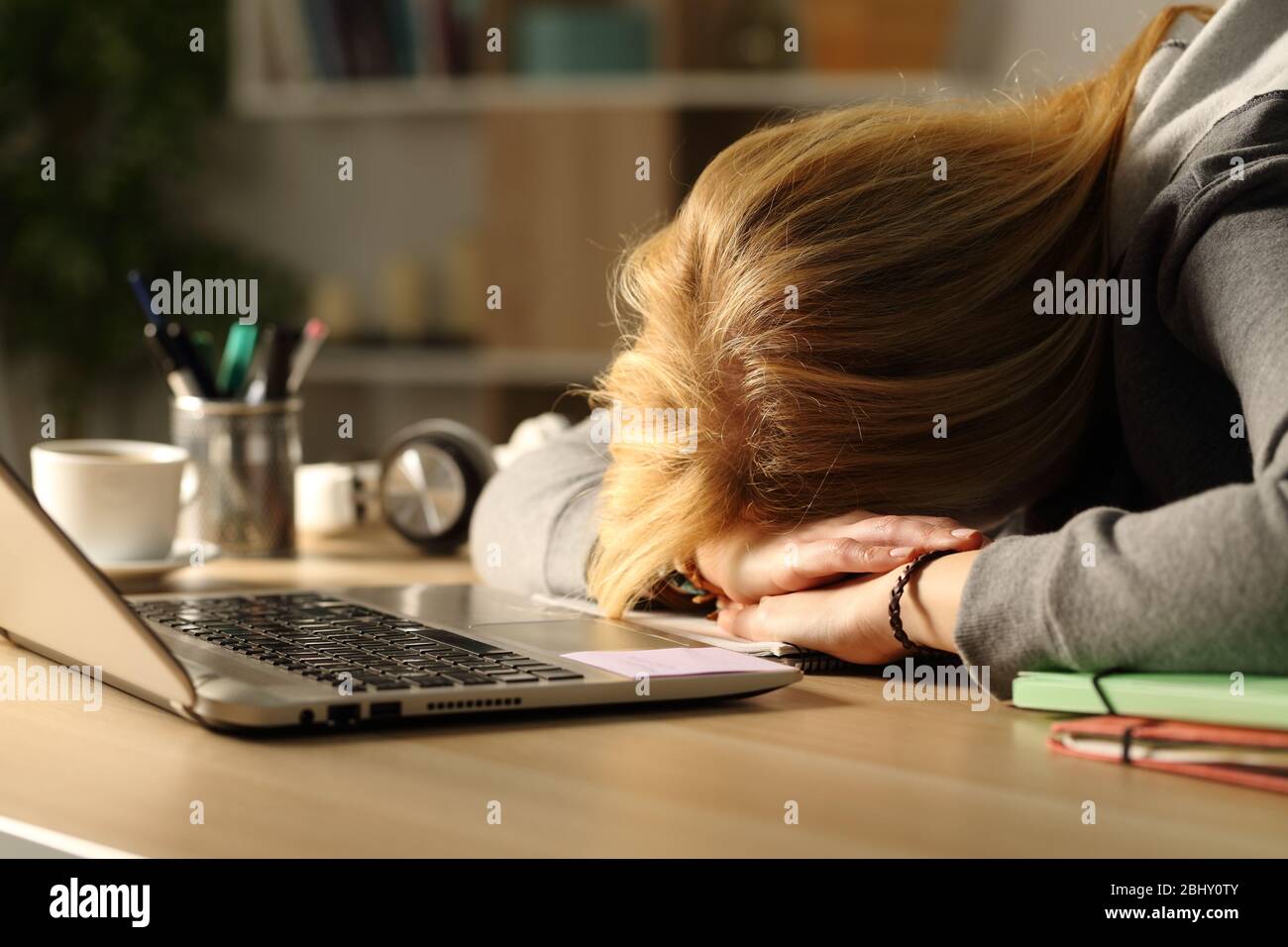 Primer plano de una niña estudiante cansada durmiendo sobre el escritorio en casa por la noche Foto de stock