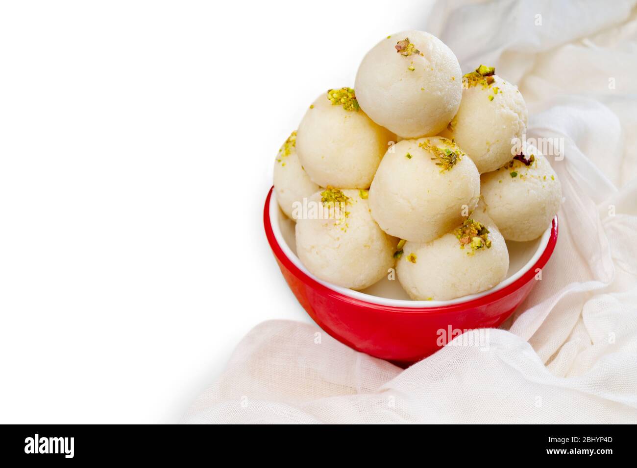 Boca regando rasgullas blancas mantenidas en un tazón con pistachos rociados. Foto de stock