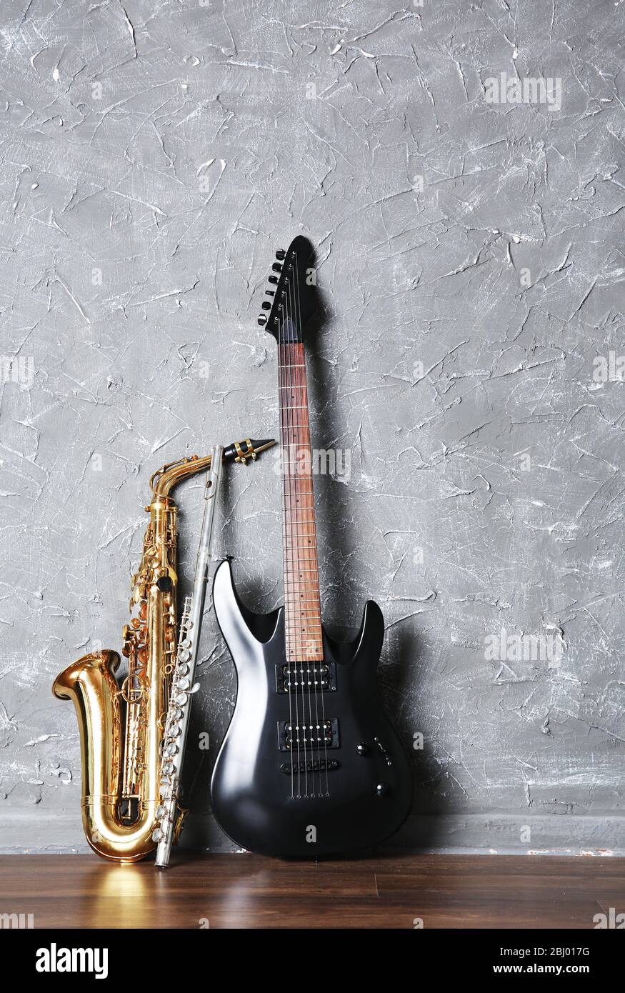 Guitarra eléctrica, flauta y saxofón sobre fondo gris de pared Fotografía  de stock - Alamy