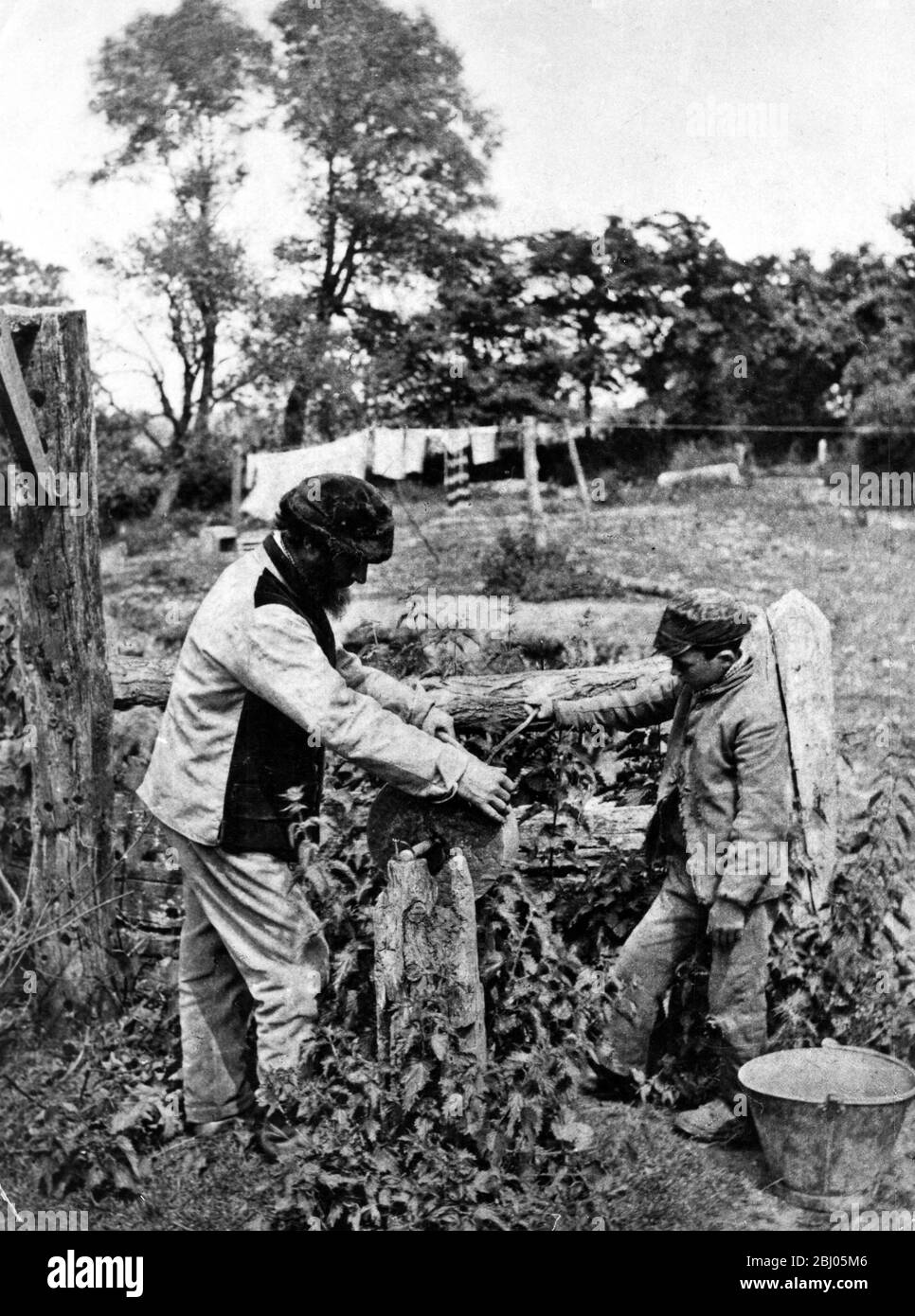 Campesino de Suffolk afilando su hierro en una piedra de afilar comunal. Foto de stock
