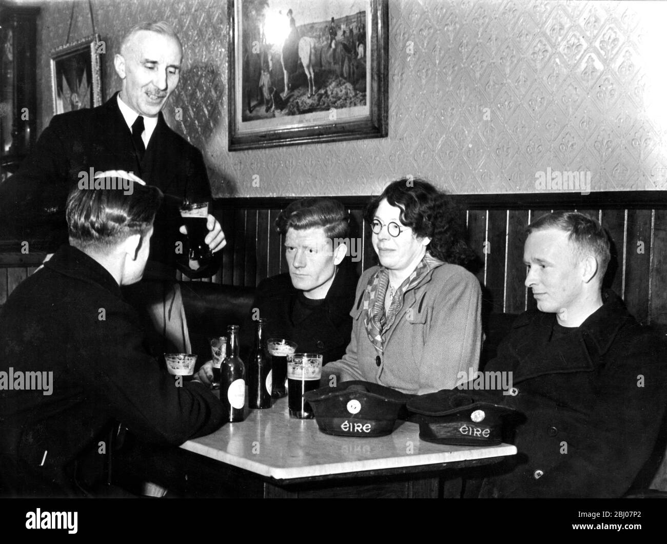 Los marineros de la marina de Eire son clientes regulares en el Bar de Downey's Select donde un strick de barmen ha durado diez años . Con sus amigas cantan canciones en el pub todas las noches. - 12 de marzo de 1949 Foto de stock