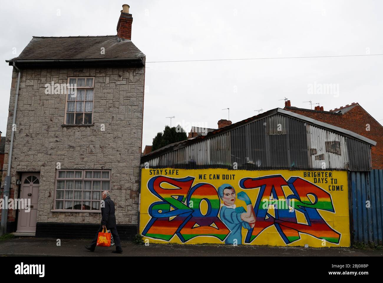 Derby, Derbyshire, Reino Unido. 28 de abril de 2020. Un hombre pasa por el arte callejero relacionado con Covid-19 durante el bloqueo de la pandemia del coronavirus. Darren Staples/Alamy Live News. Foto de stock