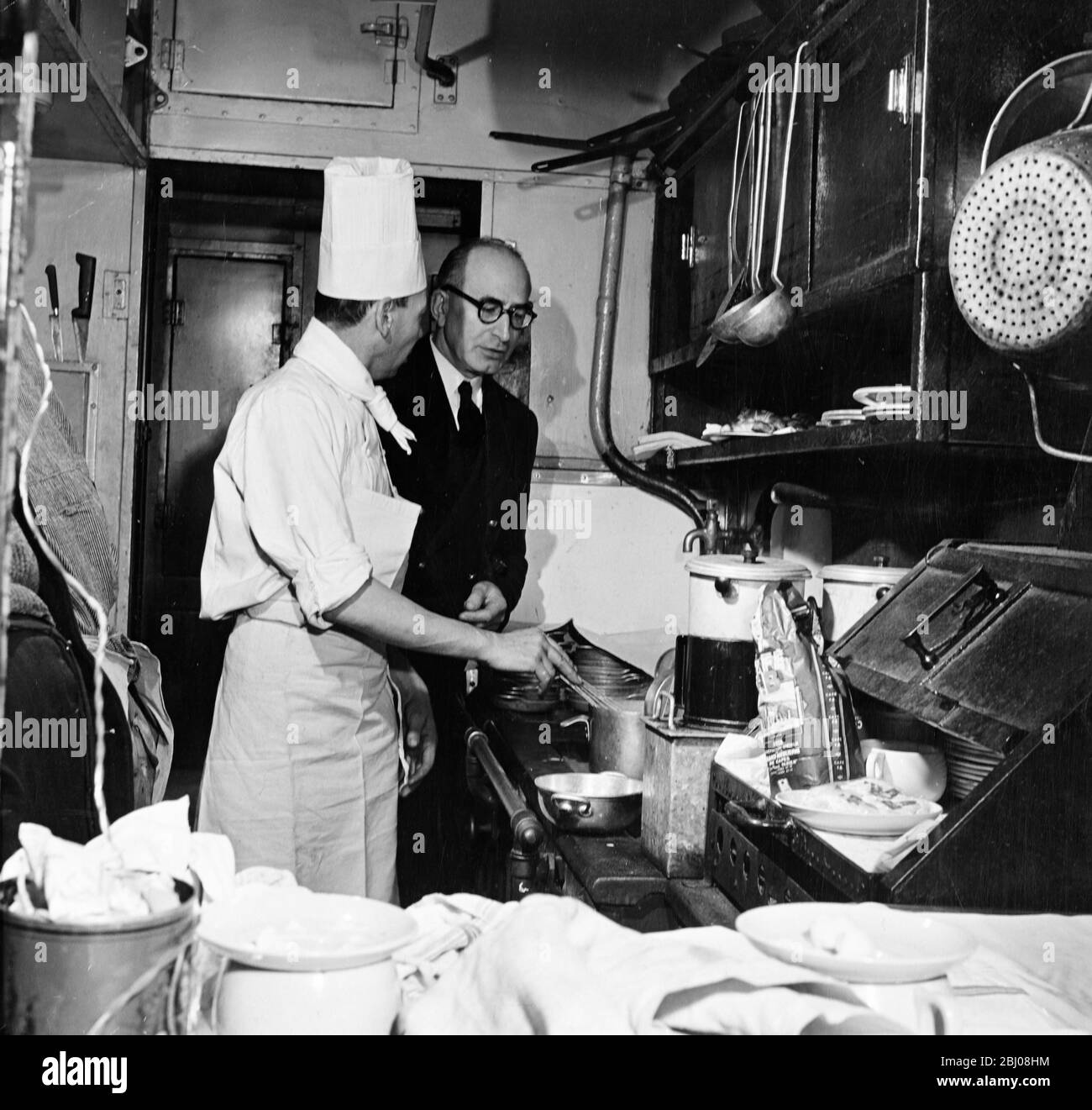 En la cocina del coche restaurante, el chef M. Roche consulta al Maitre d'Hotel sobre el desayuno. - sin fecha Foto de stock