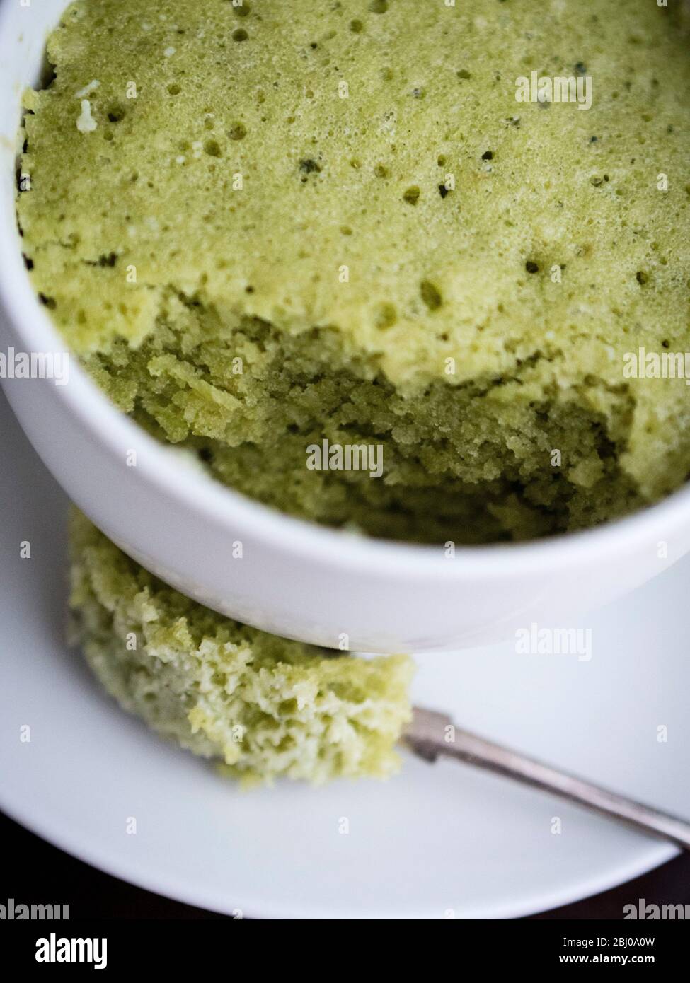 Deliciosa tarta sencilla hecha con almendras molidas y té verde matcha en polvo, horneada en una taza en un horno de microondas. Foto de stock