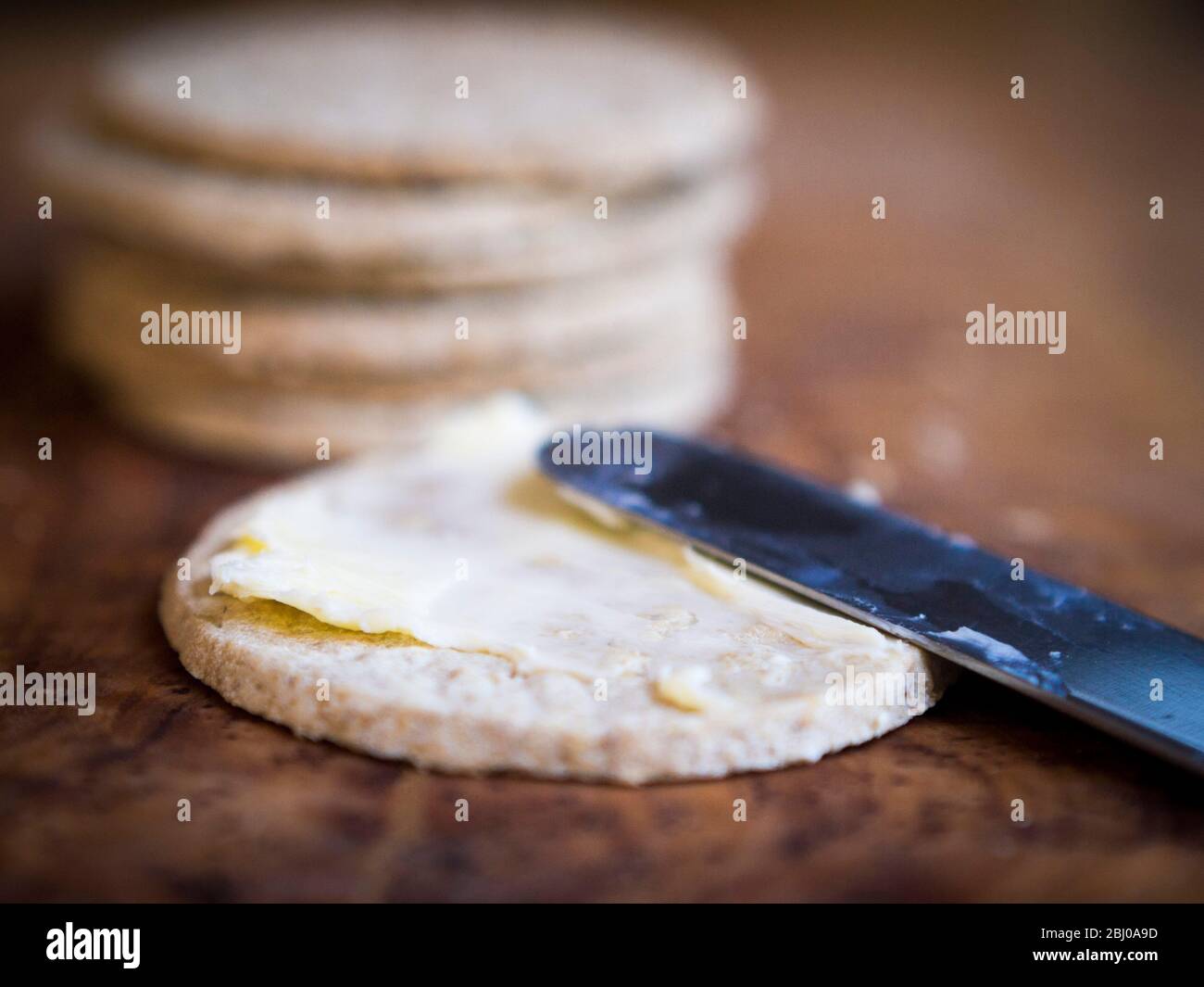 Los oatcakes de Nairn sin gluten se extienden con la mantequilla sin sal adecuada Foto de stock