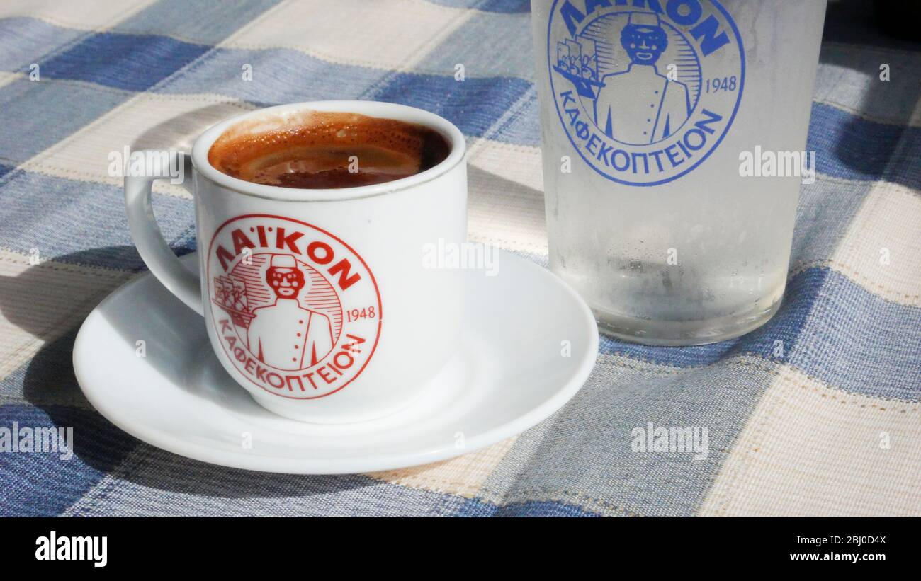 Pequeña taza de café griego fuerte, con un vaso de agua en la mesa de restaurante de la playa en el sur de Chipre - Foto de stock