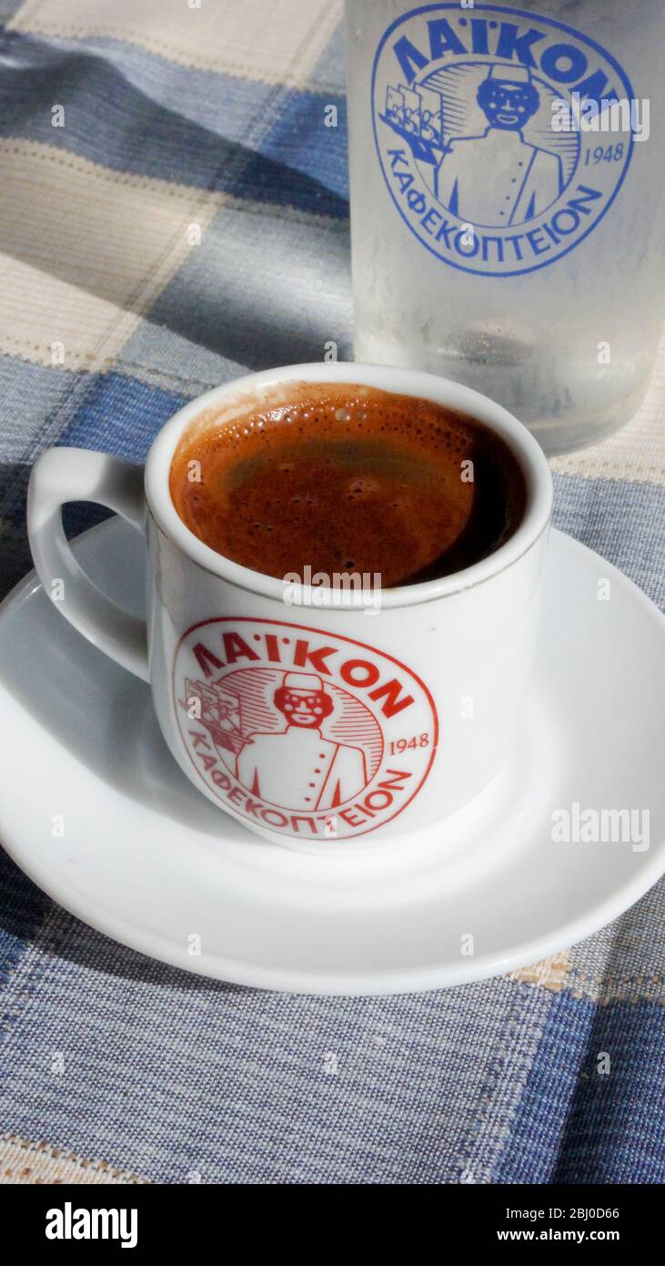 Pequeña taza de café griego fuerte, con un vaso de agua en la mesa de restaurante de la playa en el sur de Chipre - Foto de stock