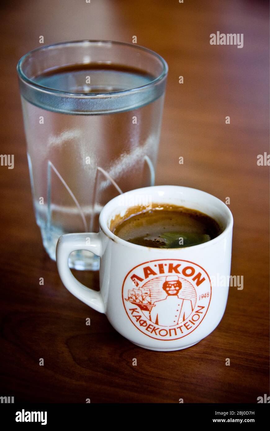 Pequeña taza de café griego fuerte, con un vaso de agua en la bandeja en la mesa de restaurante en la ladera sur de Chipre - Foto de stock