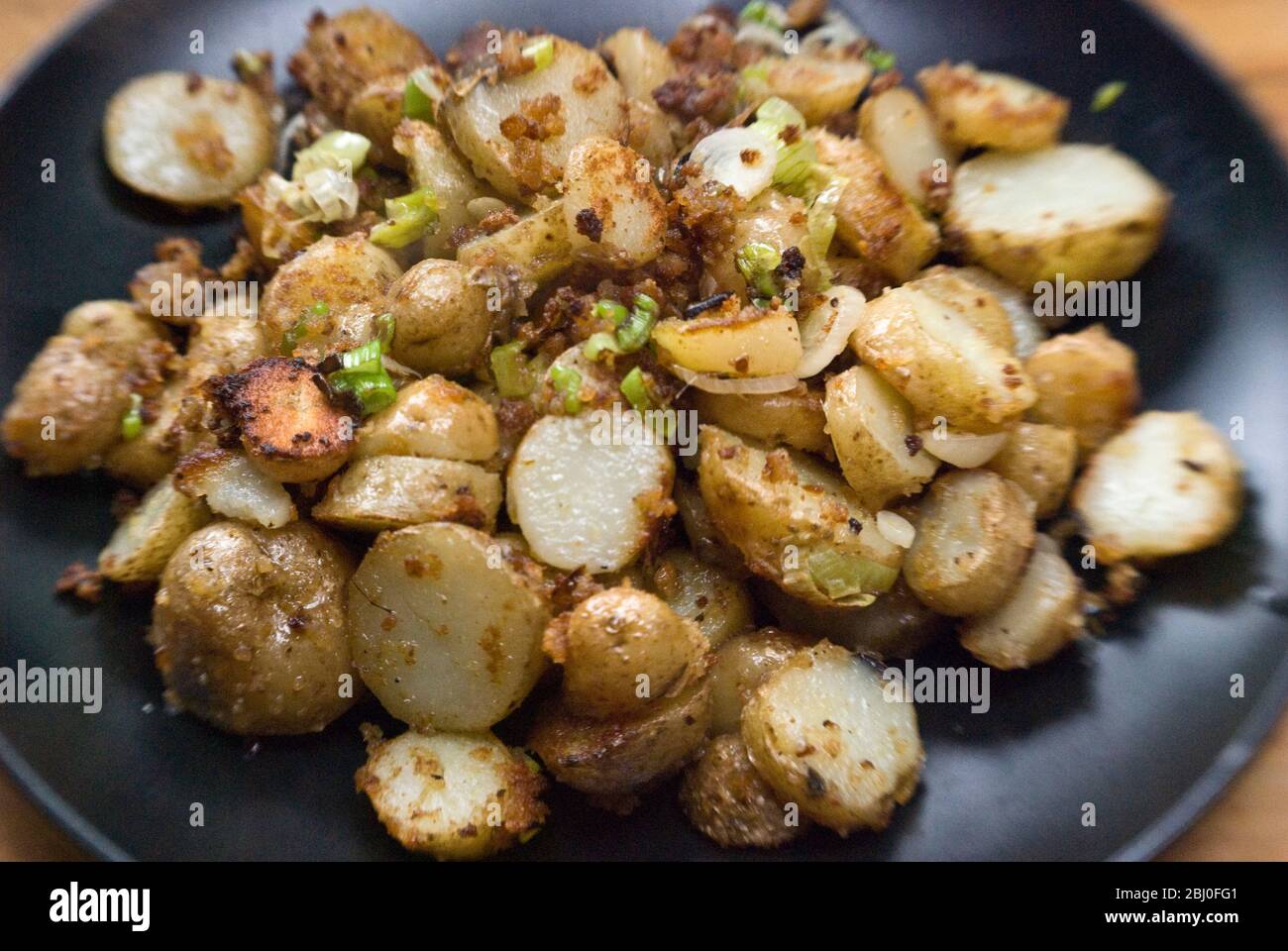 Plato de patatas fritas, salteado con anchoas, cebolletas y pan rallado. - Foto de stock