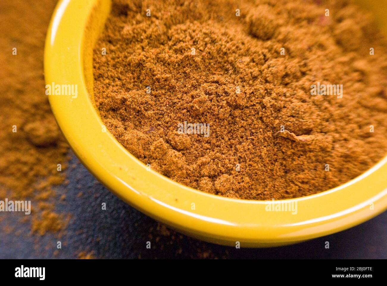 Ras-el-harnout (mezcla de especias del norte de África), en un pequeño tazón amarillo - Foto de stock