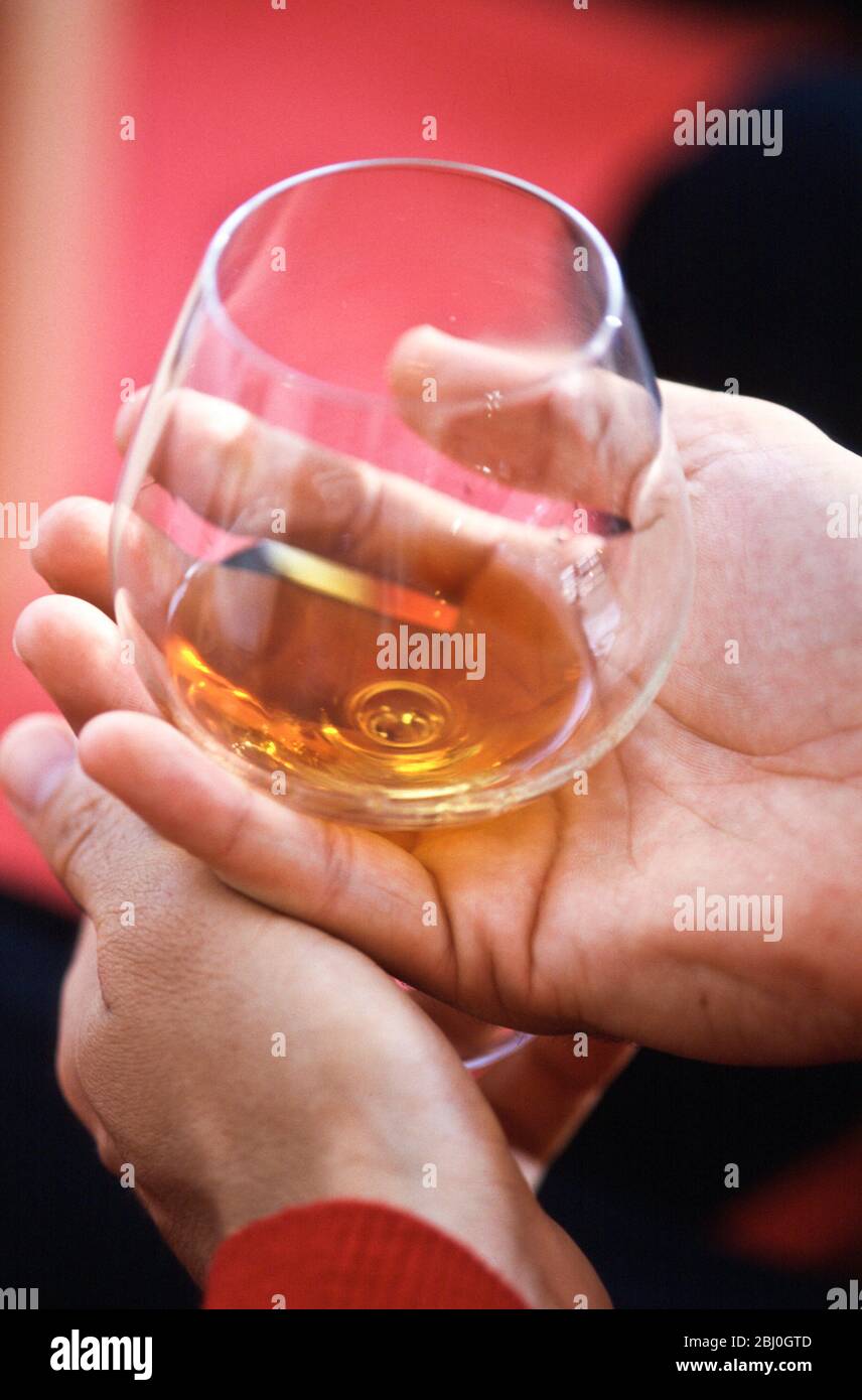 Globo de brandy tradicional que se mantiene en las manos para calentar - Foto de stock