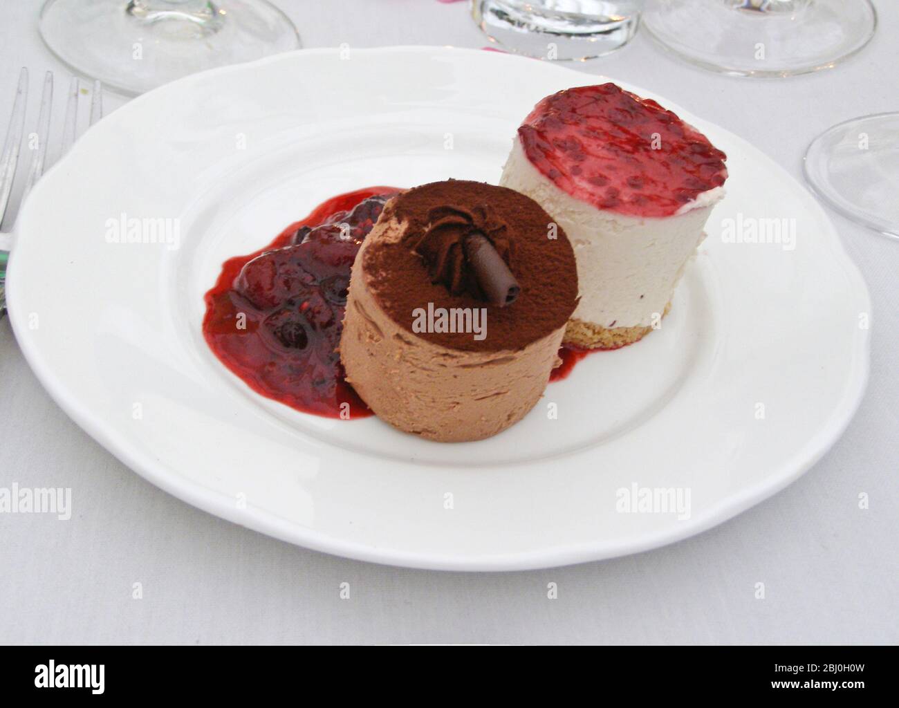 Mousses de chocolate y vainilla con coulis de frutas de consumo - postre en recepción de boda - Foto de stock