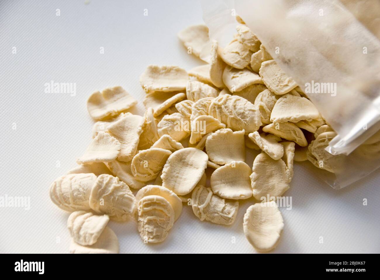 Pasta de orecchiete seca y sin cocinar sobre superficie blanca - Foto de stock