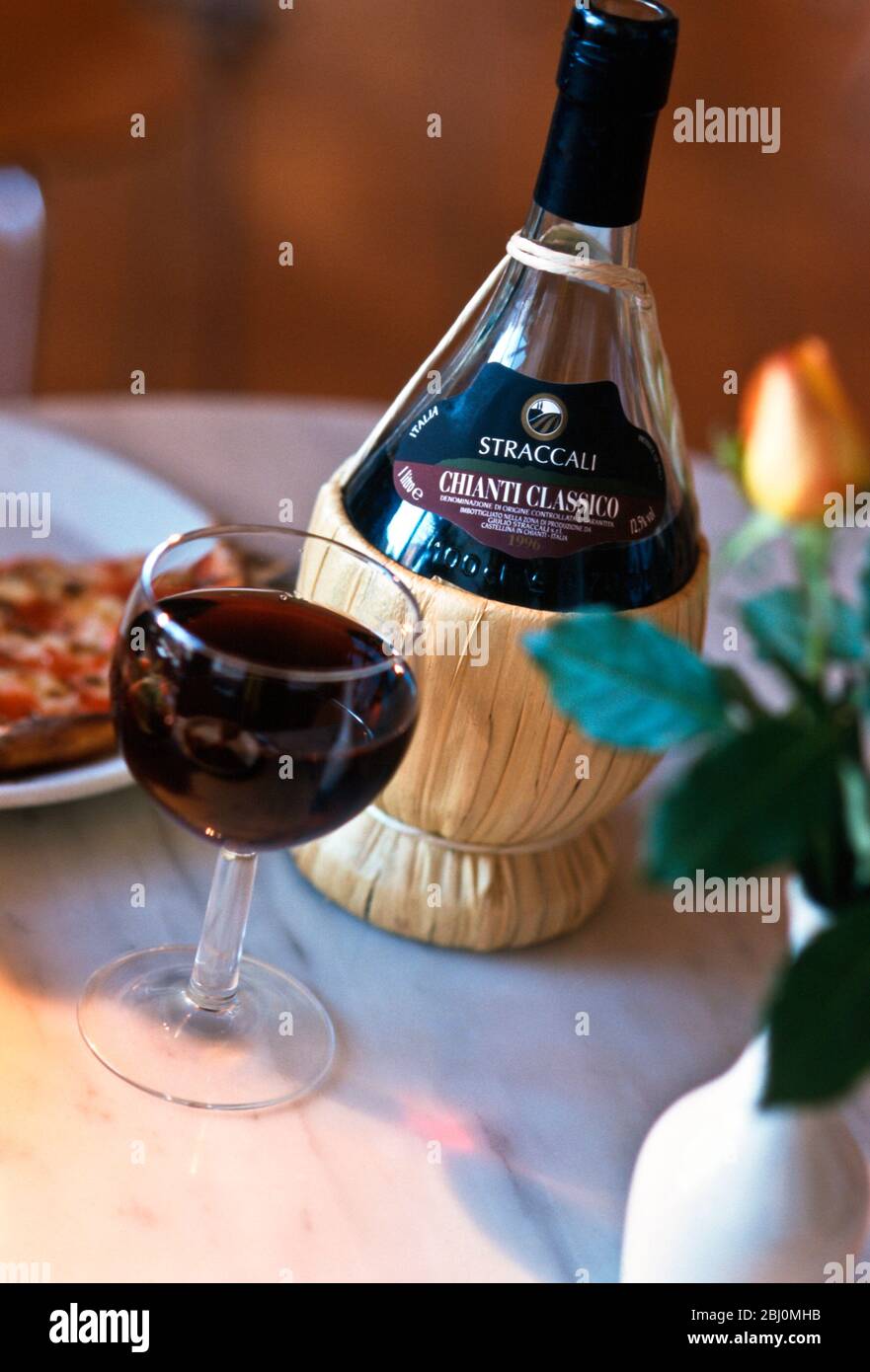 Botella de Chianti tradicionalmente embotellada en la mesa del restaurante italiano - Foto de stock