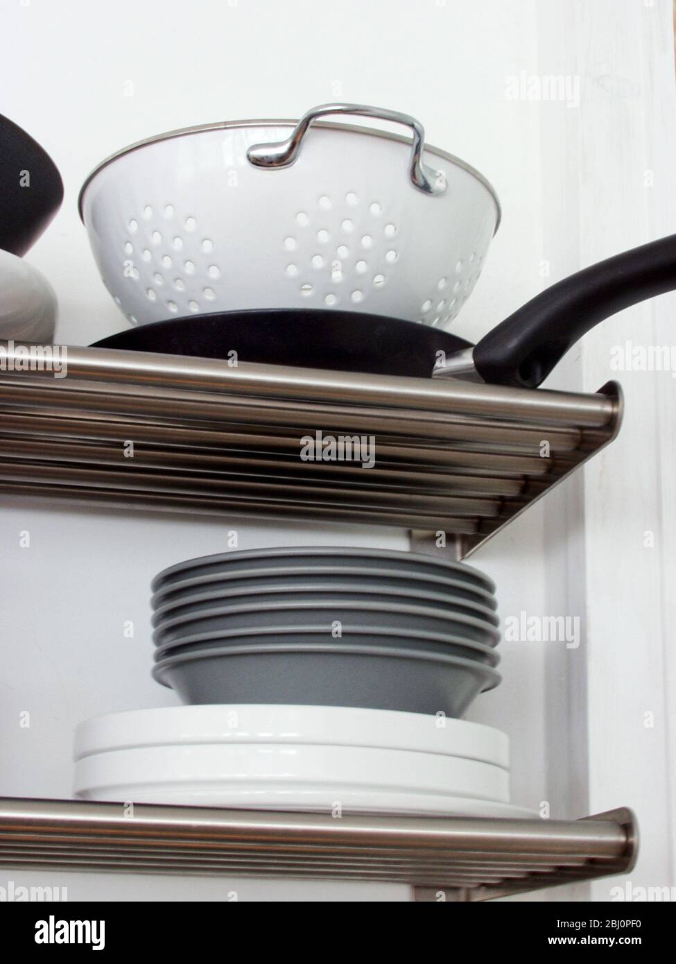 Estantes de cocina de acero inoxidable modernos con pilas de platos y utensilios - Foto de stock
