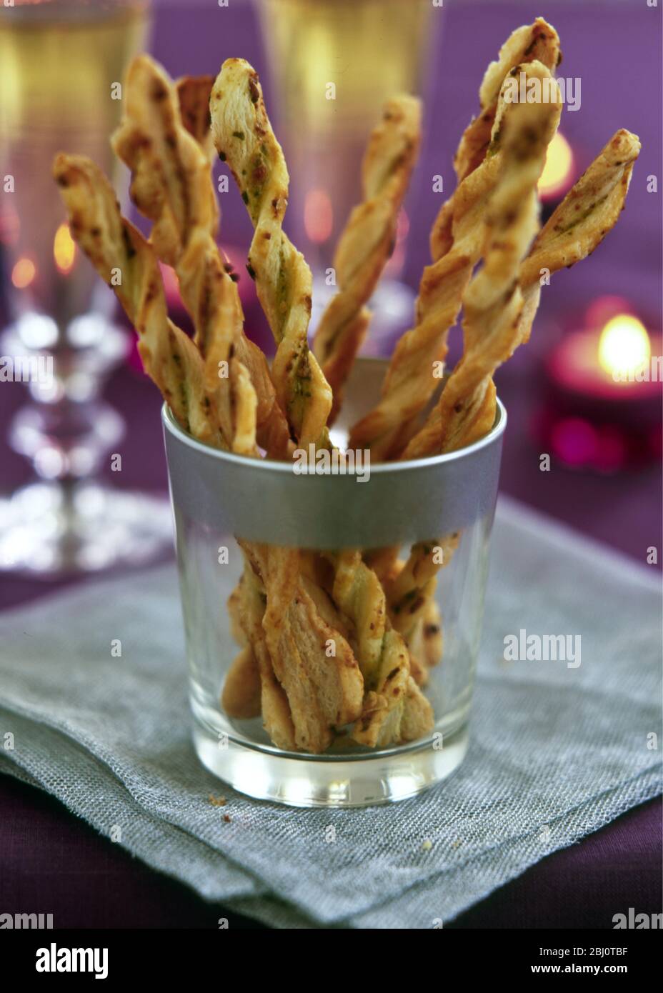 Torcidas pajitas de queso en cristal plateado con borde en un ambiente de fiesta a la luz de las velas - Foto de stock