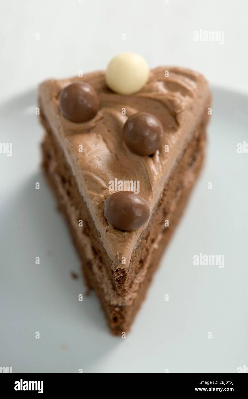 Una rebanada de pastel de chocolate con una capa de crema de mantequilla de chocolate - Foto de stock