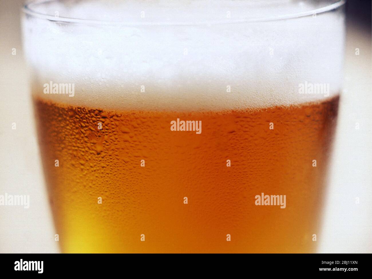 Detalle de primer plano de un vaso de cerveza o una cerveza con cabeza espumosa - Foto de stock