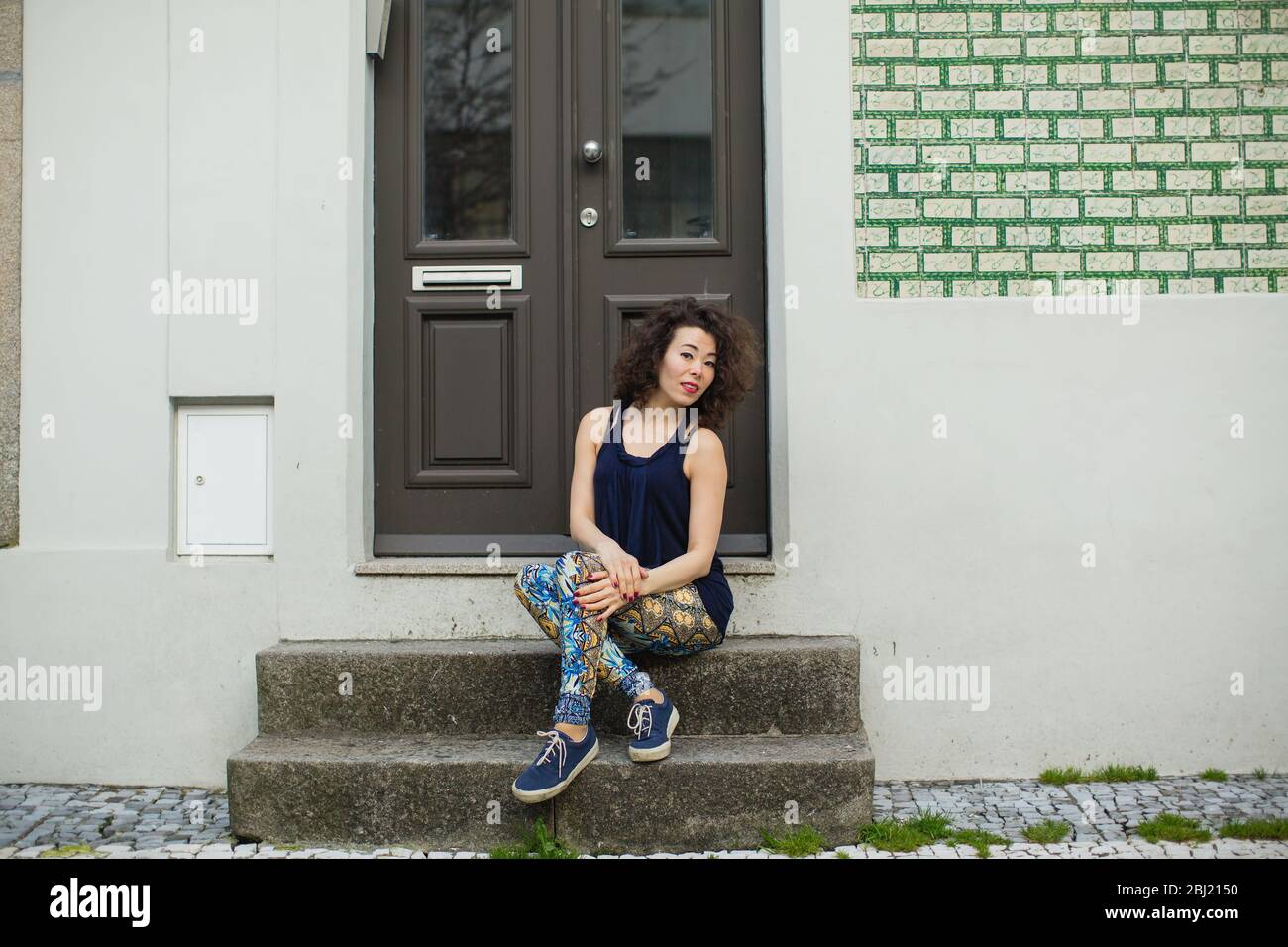 Mujer asiática joven en leggings y zapatillas de deporte en Porto Street,  Portugal. Calentamiento cerca de la pared. Hermosa mujer multicultural  alegre Fotografía de stock - Alamy