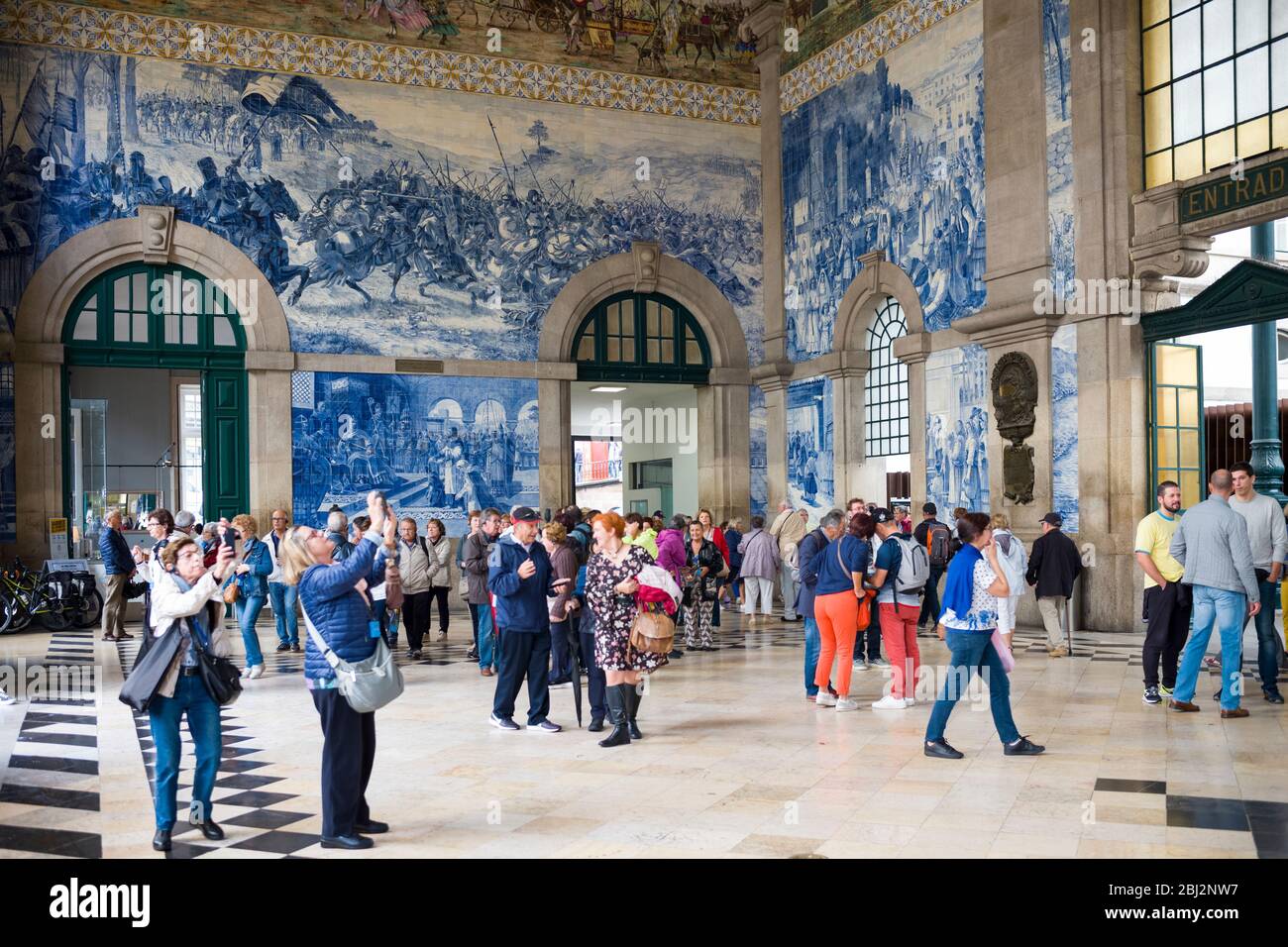 Turistas fotografiando famosos azulejos tradicionales portugueses azulejos de pared azul y blanco Sao Bento estación de tren en Oporto, Portugal Foto de stock