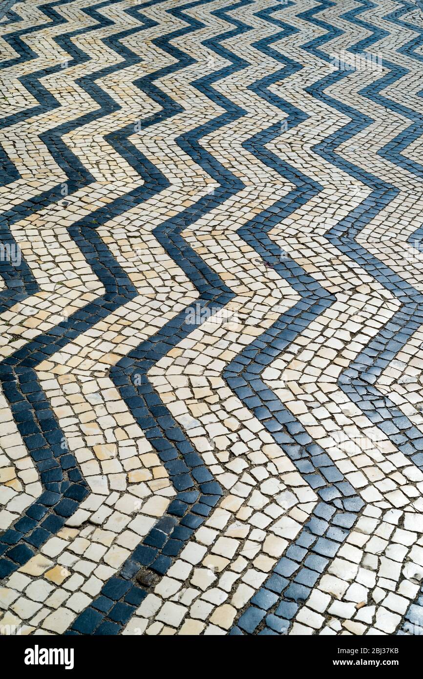Las baldosas geométricas forman formas y patrones de líneas onduladas en baldosas de pavimentación en Aveiro, Portugal Foto de stock