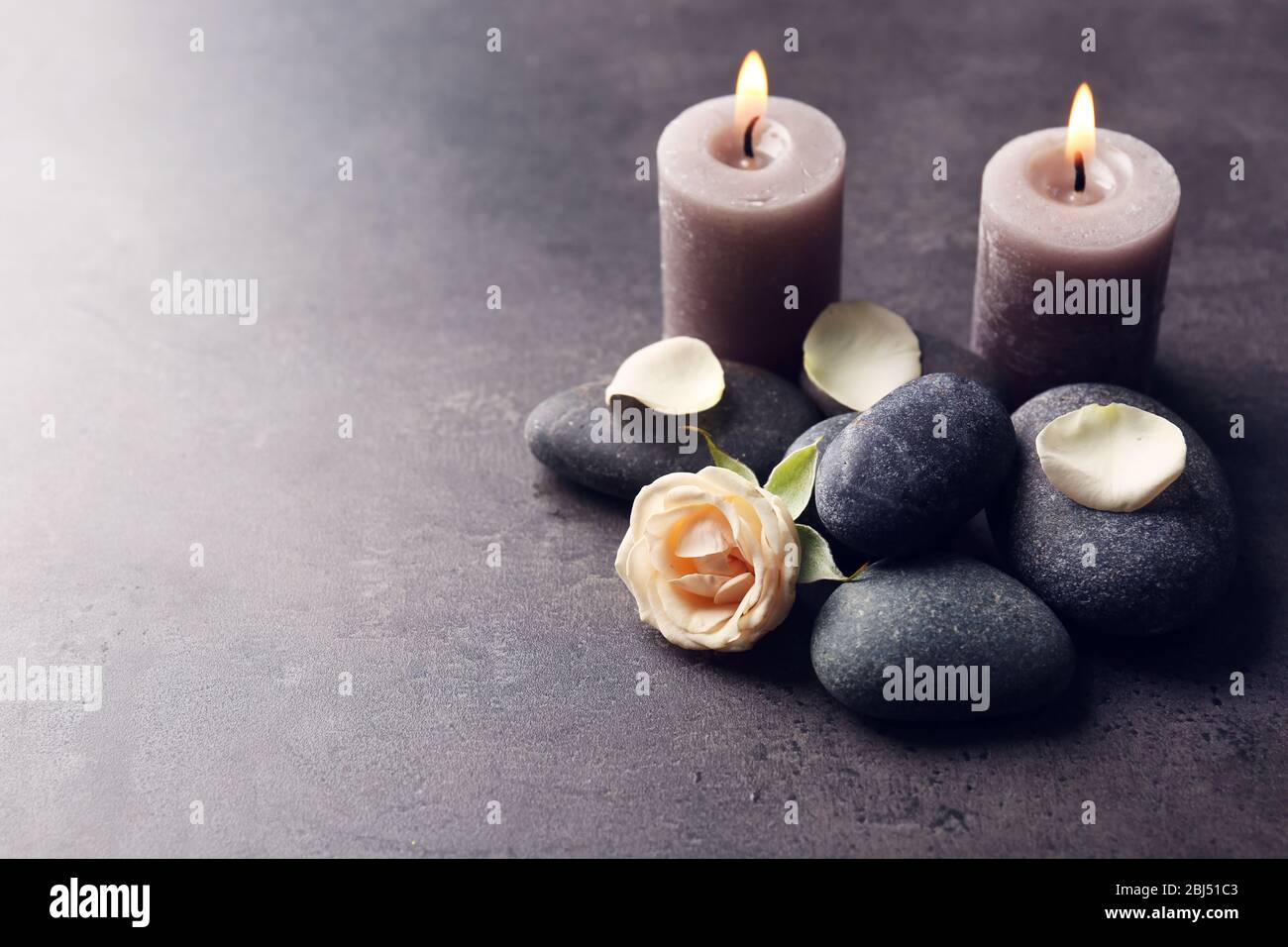 Concepto Relax - composición de velas aromáticas con guijarros y flores  sobre fondo gris Fotografía de stock - Alamy