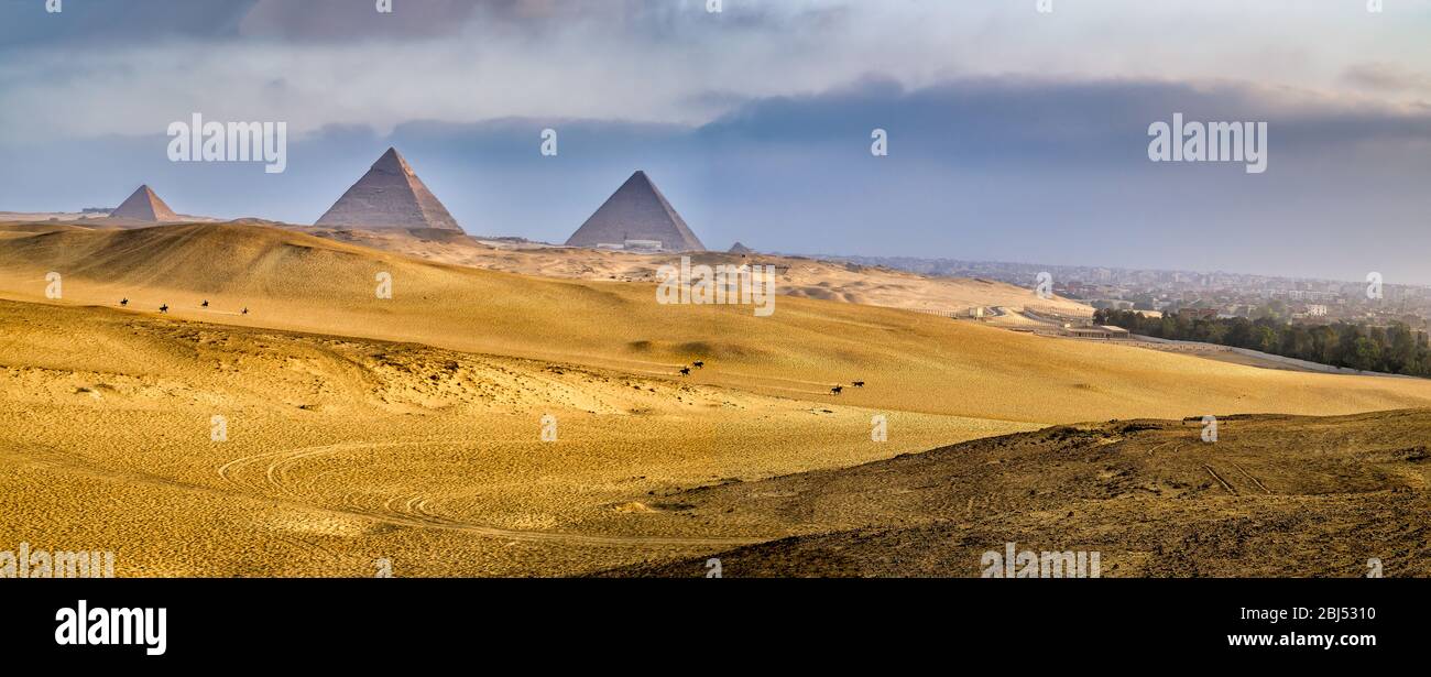 Paisaje desértico alrededor de las pirámides de Giza justo después del amanecer con un horizonte cubierto de humo de el Cairo de fondo Foto de stock