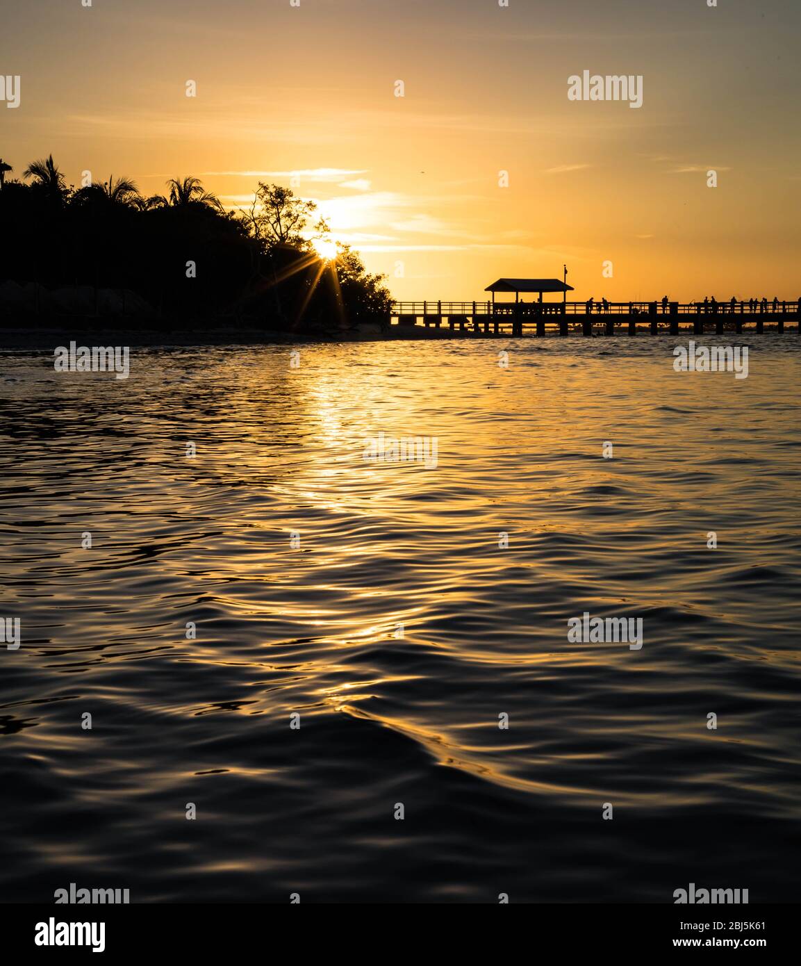 Puesta de sol en el océano de Florida con bosque y muelle Foto de stock