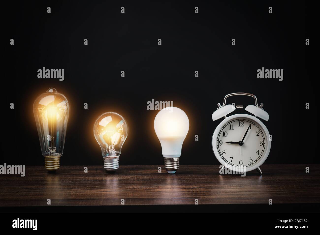 bombilla con reloj de alarma blanco sobre mesa de madera sobre fondo negro,  tiempo para la innovación y la idea para el éxito Fotografía de stock -  Alamy