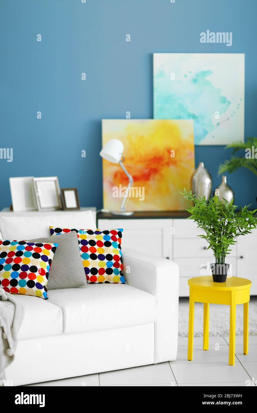 Sala de estar interior con muebles blancos, plantas verdes y cuadros sobre  fondo azul de la pared Fotografía de stock - Alamy