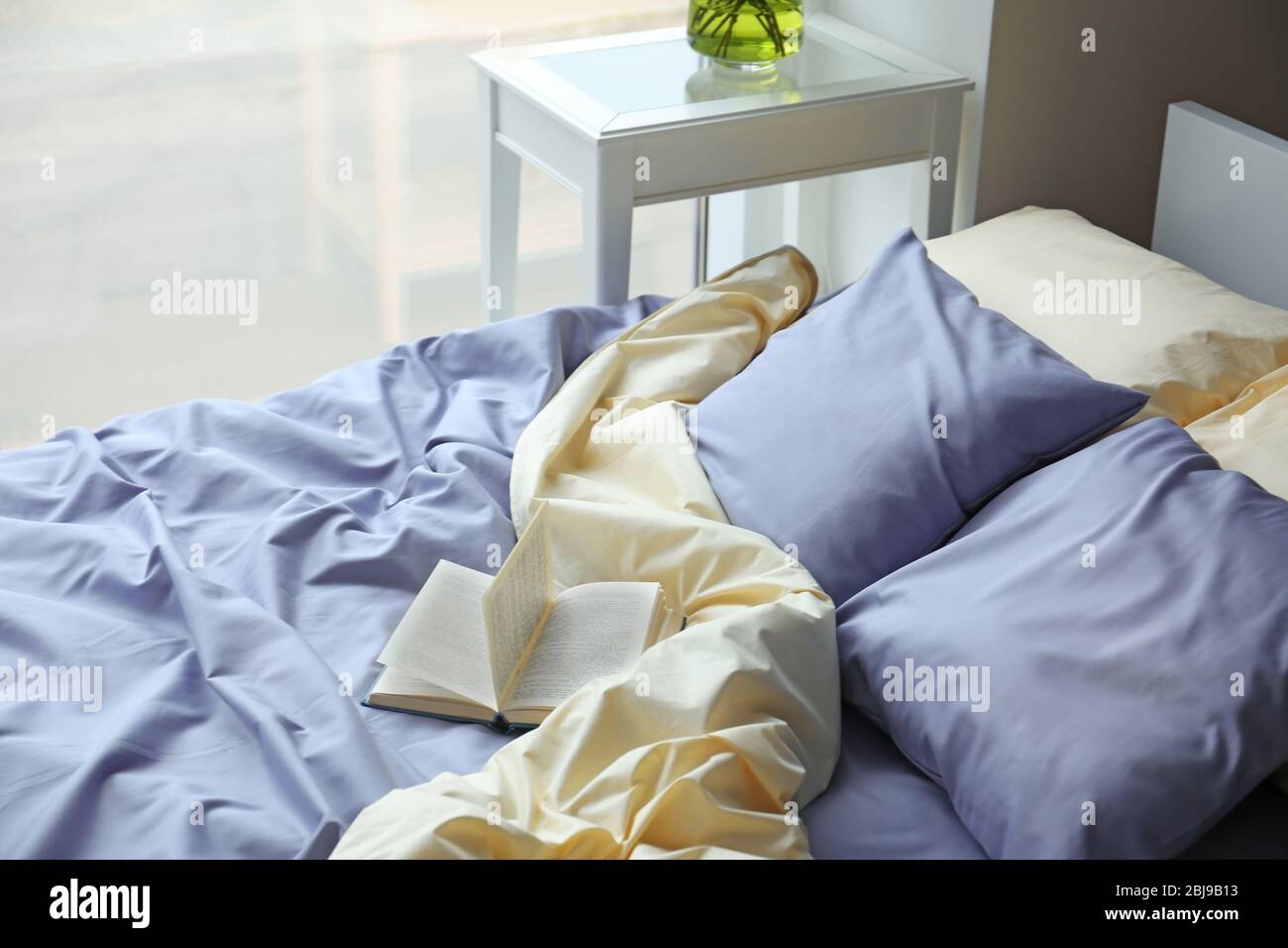 Cama sin hacer con ropa de cama azul arrugada y libro Fotografía de stock -  Alamy