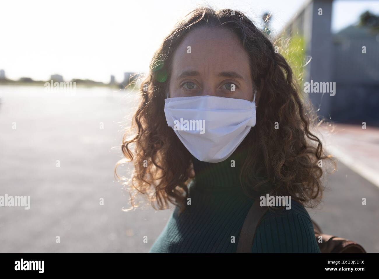 Mujer caucásica con máscara protectora y mirando la cámara Foto de stock