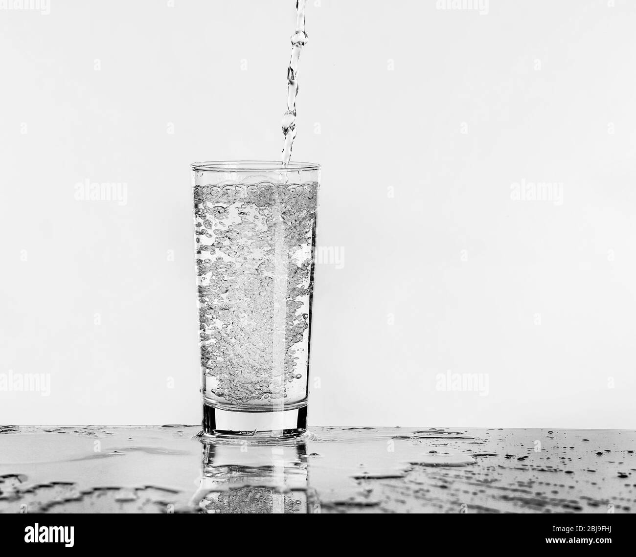 Verter agua en el cristal sobre fondo claro Foto de stock