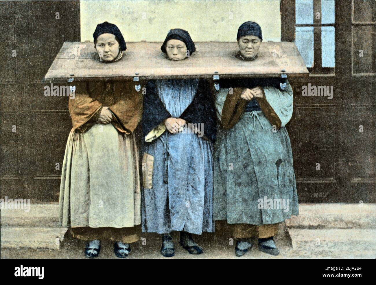Tres mujeres o mujeres prisioneros vietnamitas que usan una Cangue o Tcha, una forma de cuello de canilla o almohada utilizada como castigo o tortura de prisioneros en Vietnam y en otras partes del sudeste asiático c1890 Foto de stock