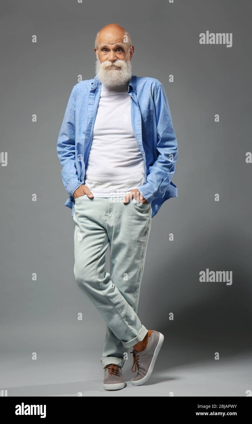 gravedad Estricto Palacio Hombre mayor con ropa elegante sobre fondo gris Fotografía de stock - Alamy