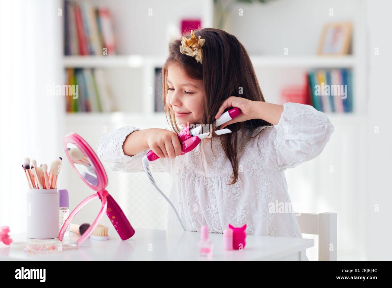 hermosa niña, niño rizado el pelo con el rizador de hierro y juguete de  belleza sistema Fotografía de stock - Alamy