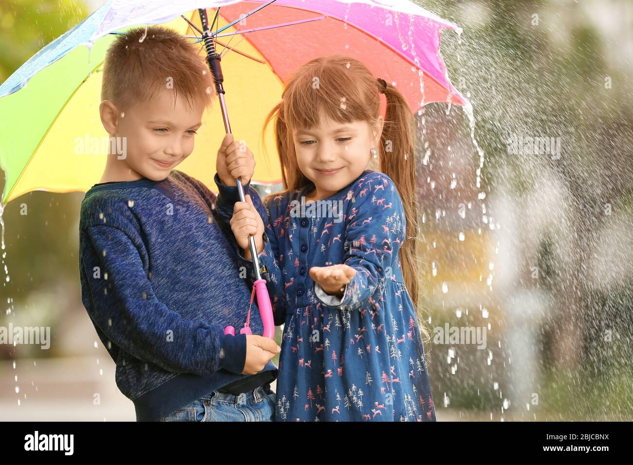 Retrato de niños lindos con paraguas bajo la lluvia Fotografía de stock -  Alamy